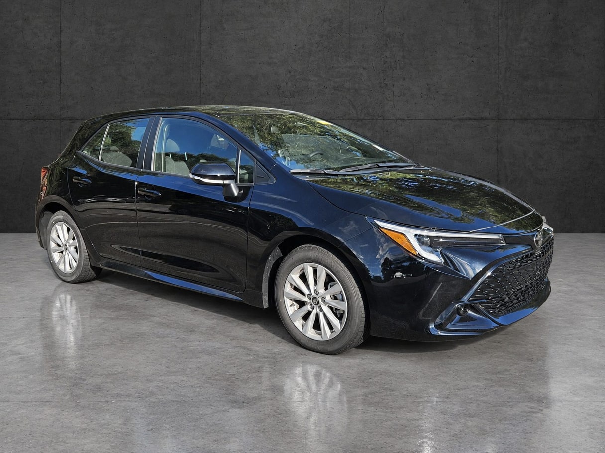 The same Corolla Hatchback on a polished concrete floor in front of a dark concrete panel wall.