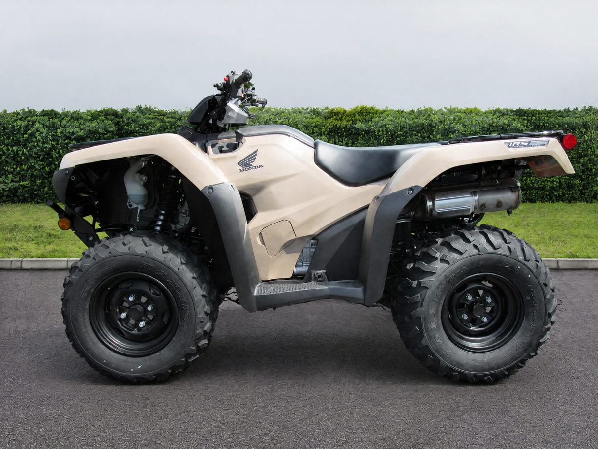 The same Rancher ATV on a road in front of a hedge and a lawn.