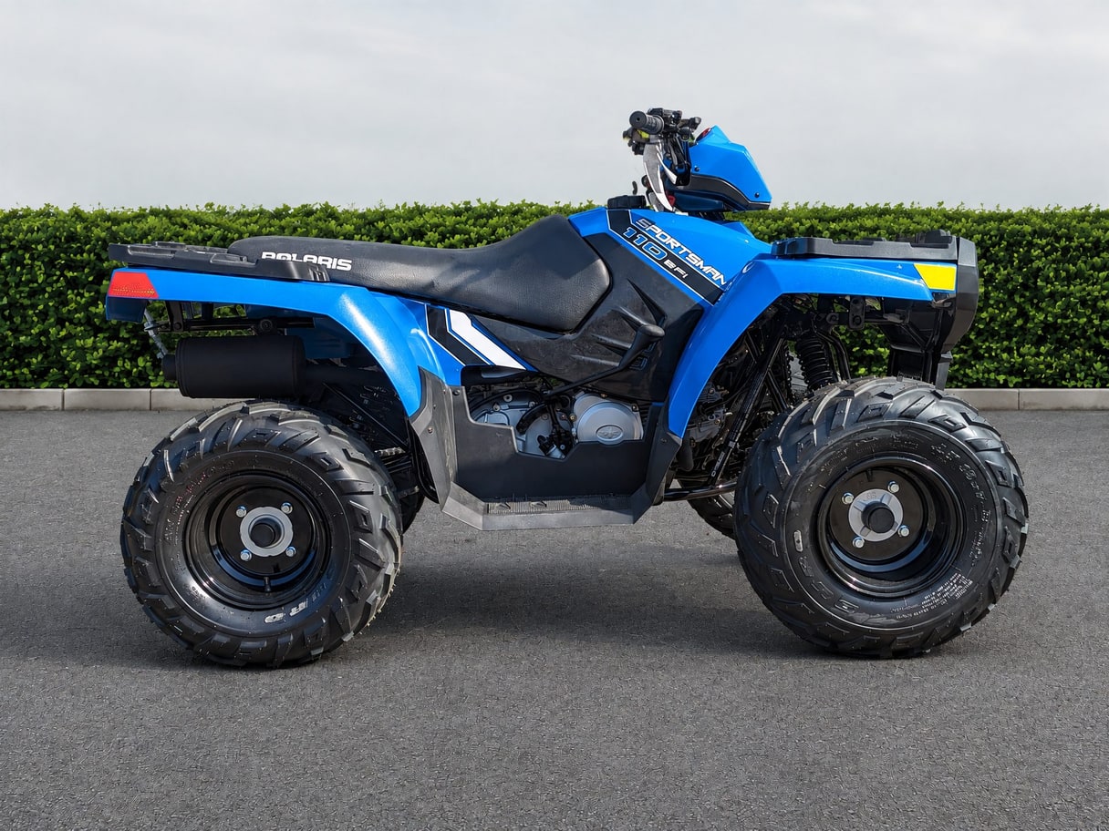 The same Sportsman ATV on plain asphalt in front of a trimmed hedge.